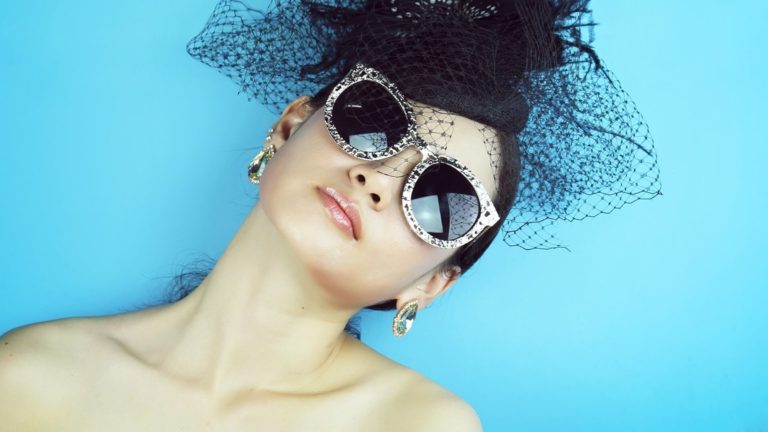 attractive widow with sunglasses and black hat tilting her head to the side