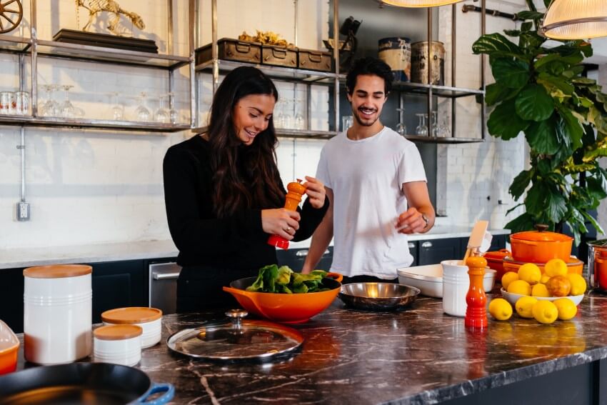 happy couple preparing a salad in their kitchen while dating vegan