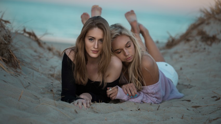 two bisexual girls cuddling at the beach