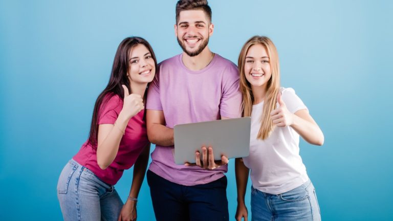 men with laptop between two women who show thumbs up