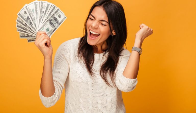 woman holds up pile of dollar bills while cheering