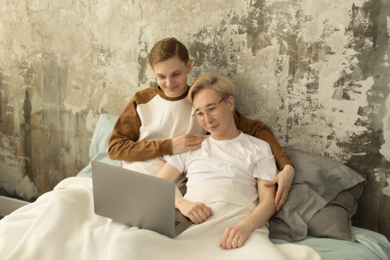 gay couple watching a movie in bed