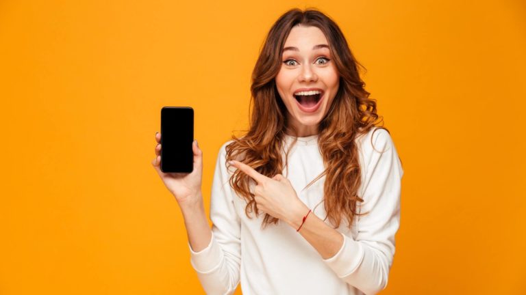 girl with long hair points to her smartphone with a happy face