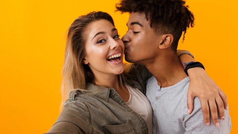 happy interracial couple cheek kiss