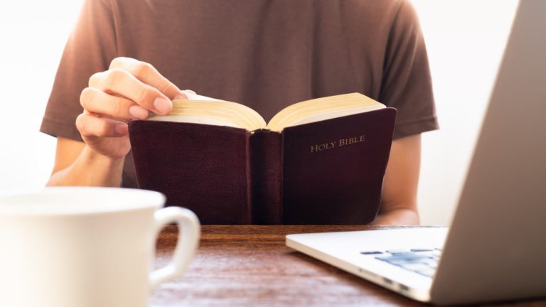 christian man reads bible while dating online on his laptop