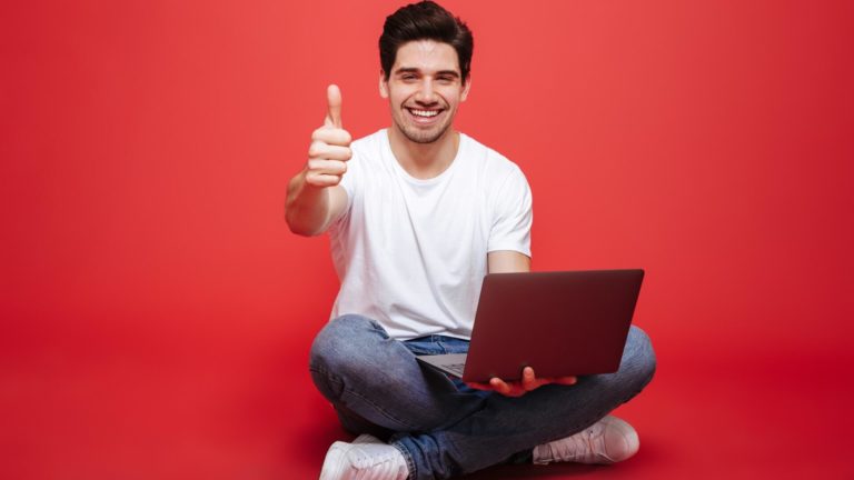 successful online dater on laptop shows thumbs up