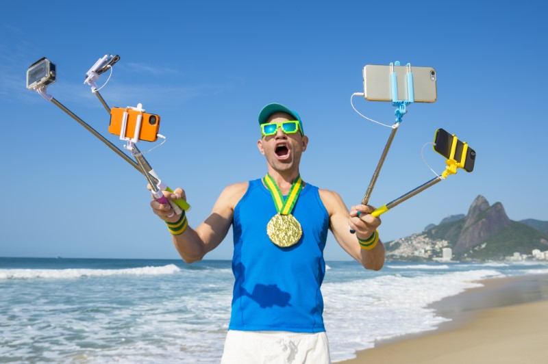 crazy guy takes funny selfie with several selfie sticks on a beach