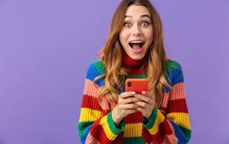 woman in pride knit sweater texts on her phone