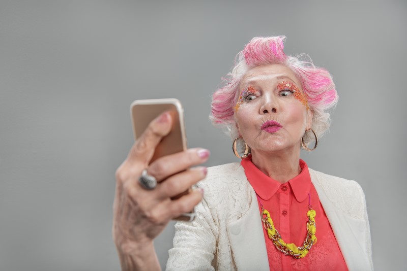 senior lady with pink hair and crazy eye makeup taking a selfie