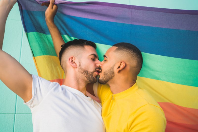gay couple kissing in front of a rainbow flag