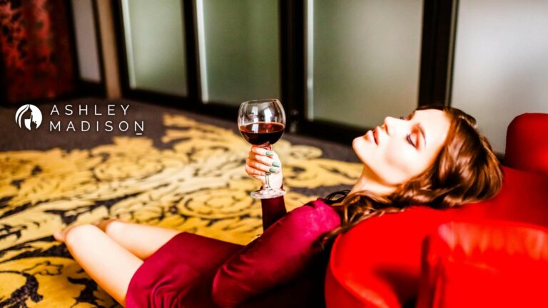 Woman enjoying red wine with Ashley Madison logo